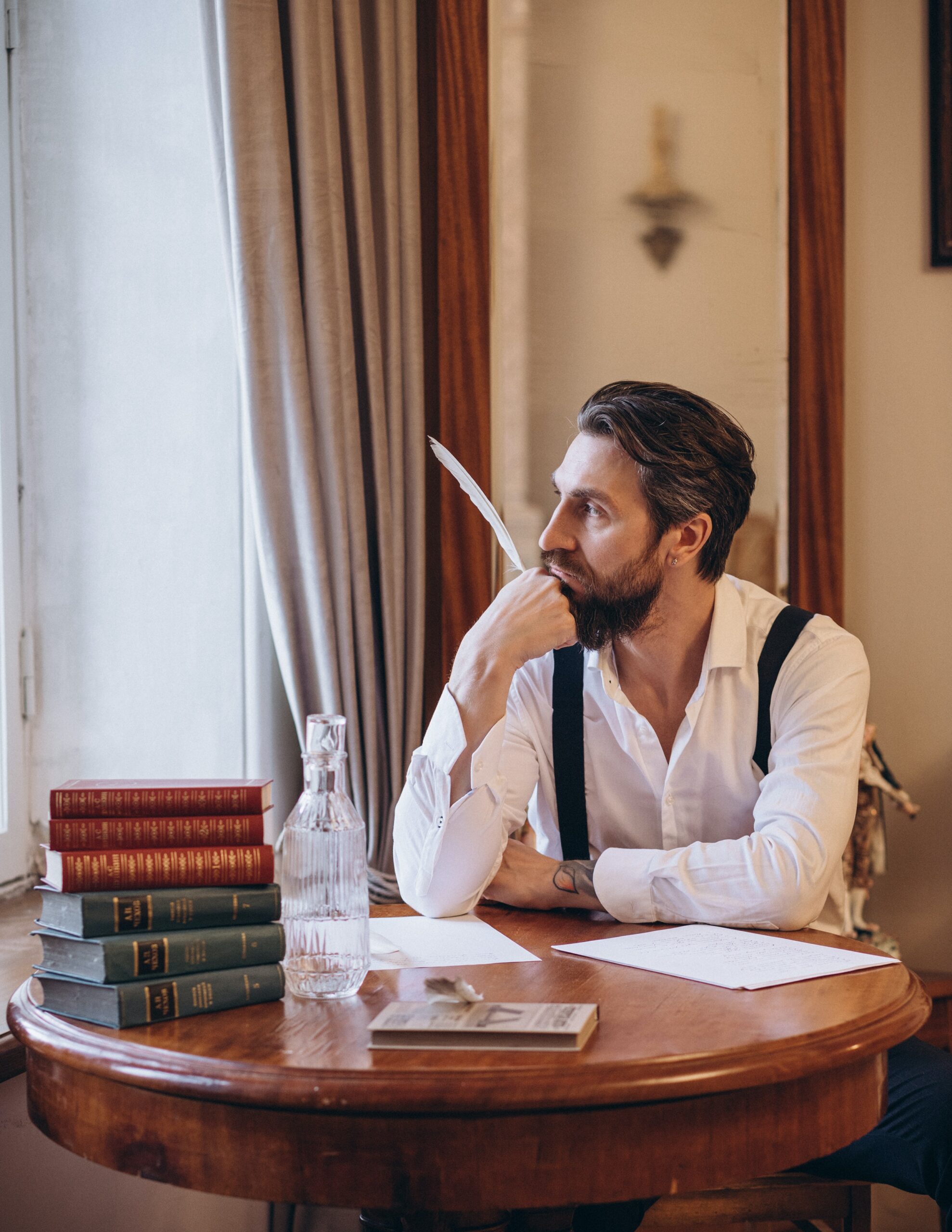 Photo of a man holding a feather looking away.